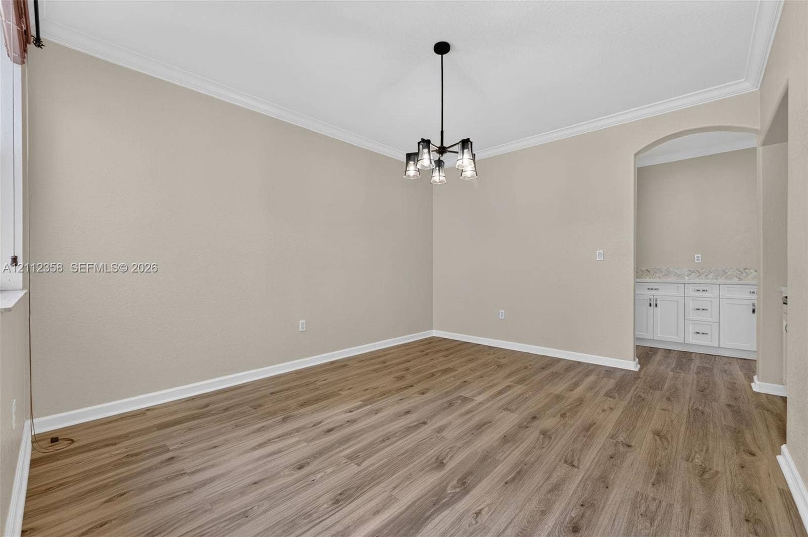 1611 SE 16th Street, Homestead, FL 33035 Interior space featuring wood-finish flooring, crown molding, a multi-light pendant fixture, and a built-in cabinetry unit with a countertop