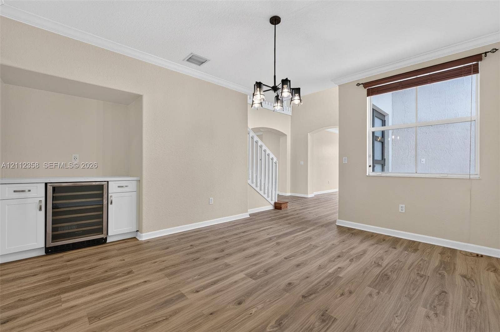 1611 SE 16th Street, Homestead, FL 33035 Wood-finish flooring, white built-in cabinetry, integrated wine refrigerator, multi-arm chandelier, and crown molding