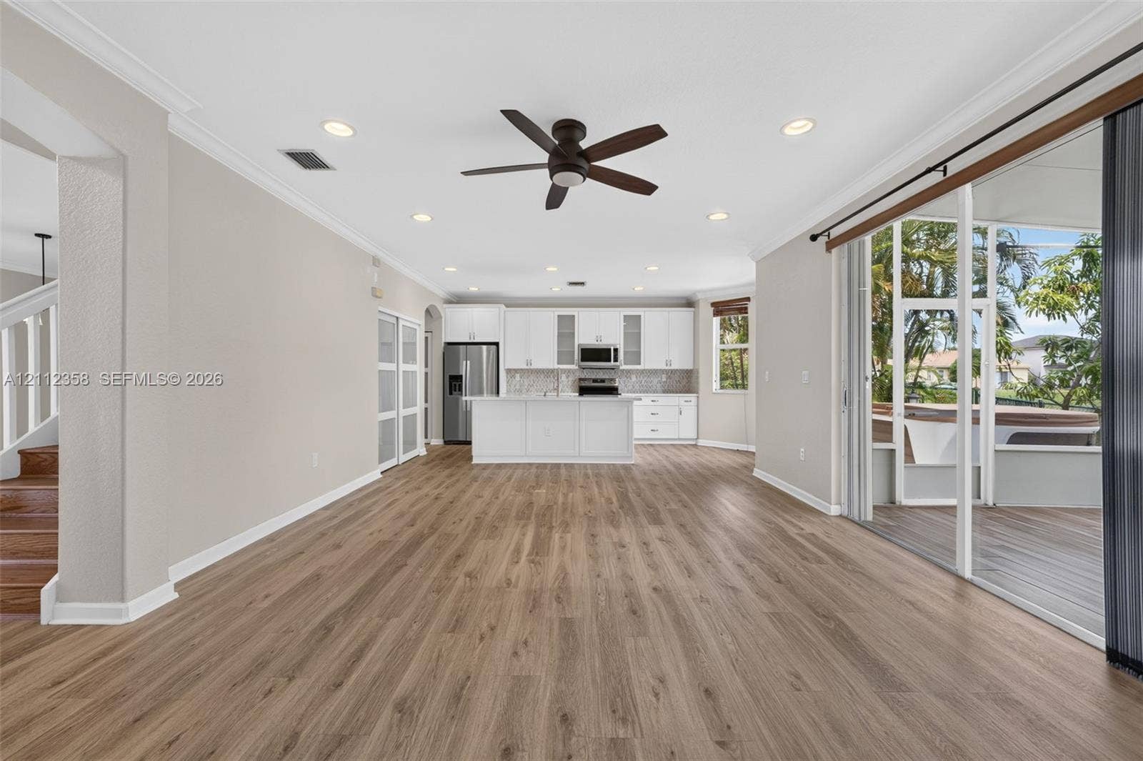 1611 SE 16th Street, Homestead, FL 33035 Open-concept interior featuring wood-finish flooring, recessed lighting, a center island kitchen with white cabinetry, and multi-panel sliding glass doors