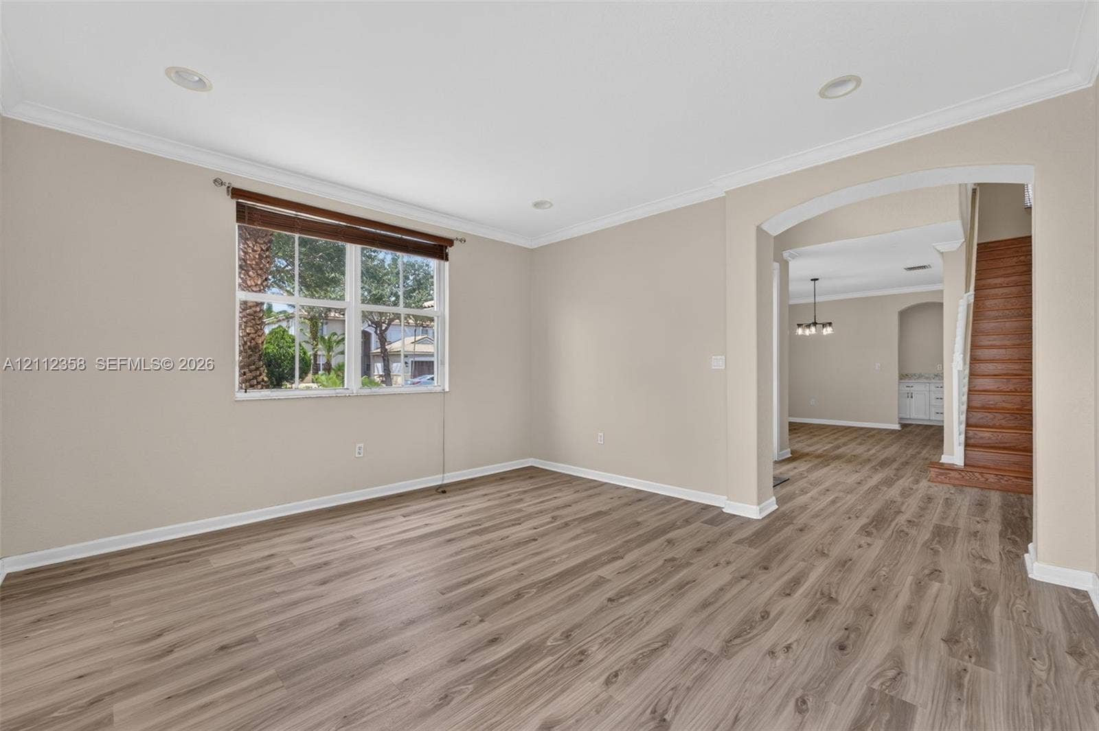 1611 SE 16th Street, Homestead, FL 33035 Open-concept space featuring wood-finish flooring, crown molding, recessed lighting, and a prominent arched entryway with wood-finish staircase