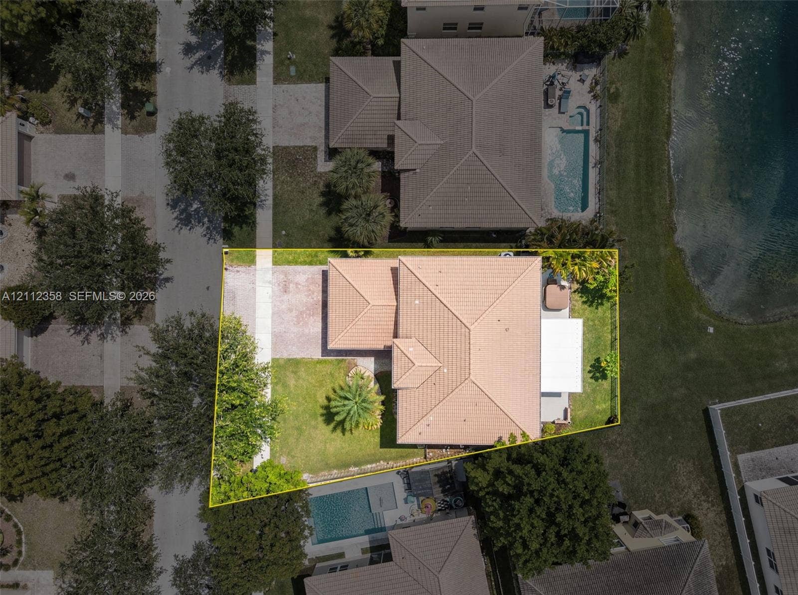1611 SE 16th Street, Homestead, FL 33035 Aerial view of property featuring a tile roof, paved driveway, landscaped lawn with mature trees, and a private backyard patio