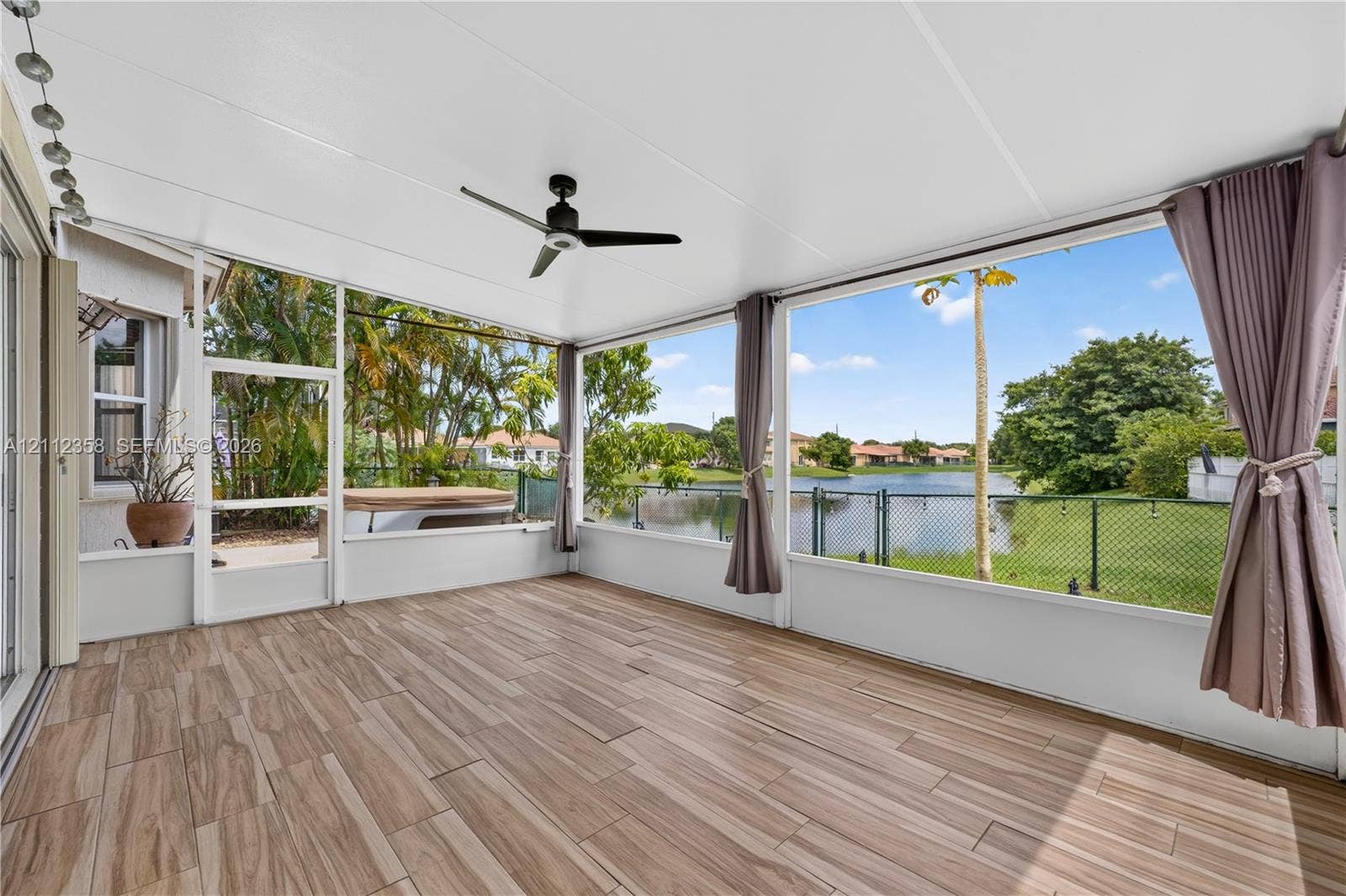 1611 SE 16th Street, Homestead, FL 33035 Screened-in lanai featuring wood-finish flooring, a ceiling fan, and large window panels overlooking the water