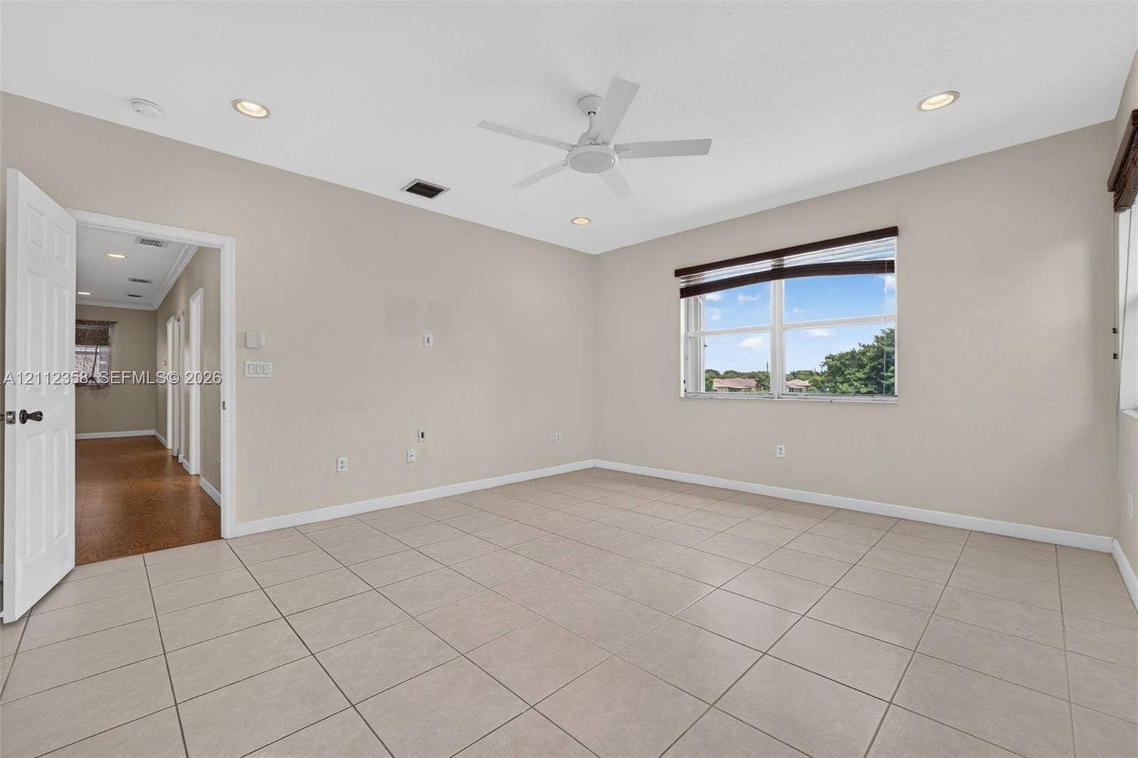 1611 SE 16th Street, Homestead, FL 33035 Spacious room featuring neutral tile flooring, recessed lighting, a white ceiling fan, and a single-pane window