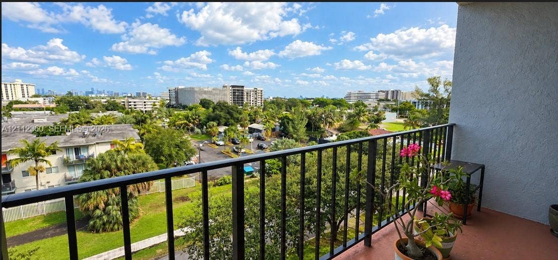 Covered balcony featuring black metal railings and concrete flooring with an expansive outdoor panorama