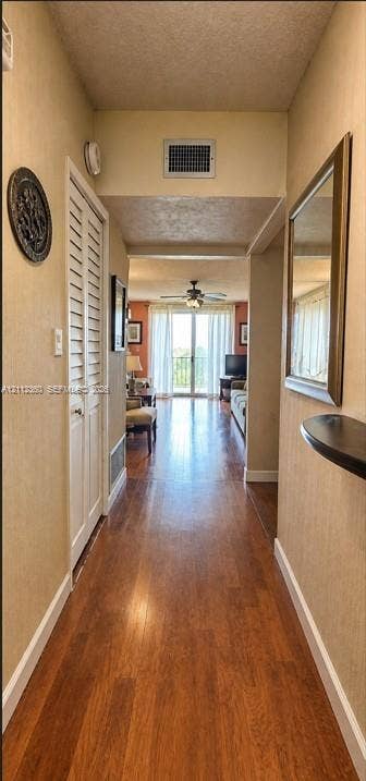 Hallway featuring wood-finish flooring, louvered bi-fold closet doors, and a built-in wall-mounted shelf