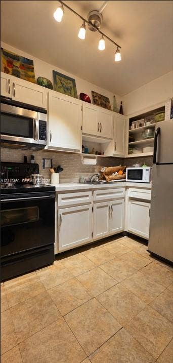 Kitchen featuring white shaker-style cabinetry, stainless steel appliances, ceramic tile flooring, a mosaic tile backsplash, and a multi-bulb track lighting fixture