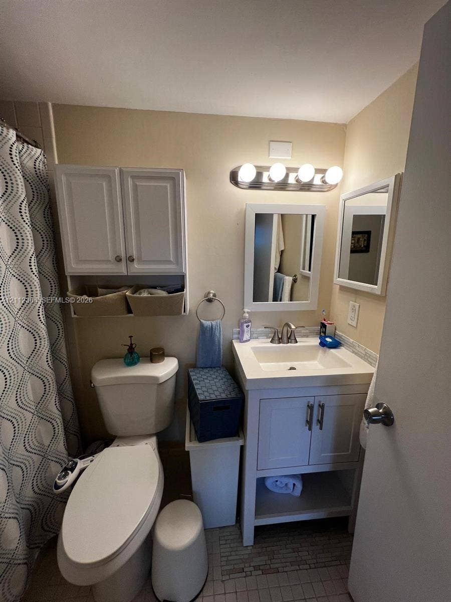 White vanity with rectangular sink, four-light vanity fixture, built-in upper cabinet storage, and framed wall mirror