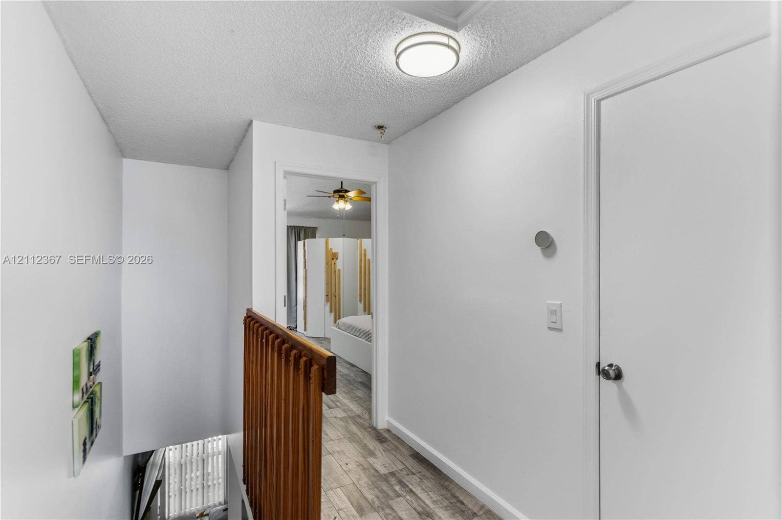 10803 Cypress Glen Drive, #10803, Coral Springs, FL 33071 Hallway featuring wood-finish flooring, a wood-slat railing, a flush-mount ceiling light fixture, and a solid-core interior door