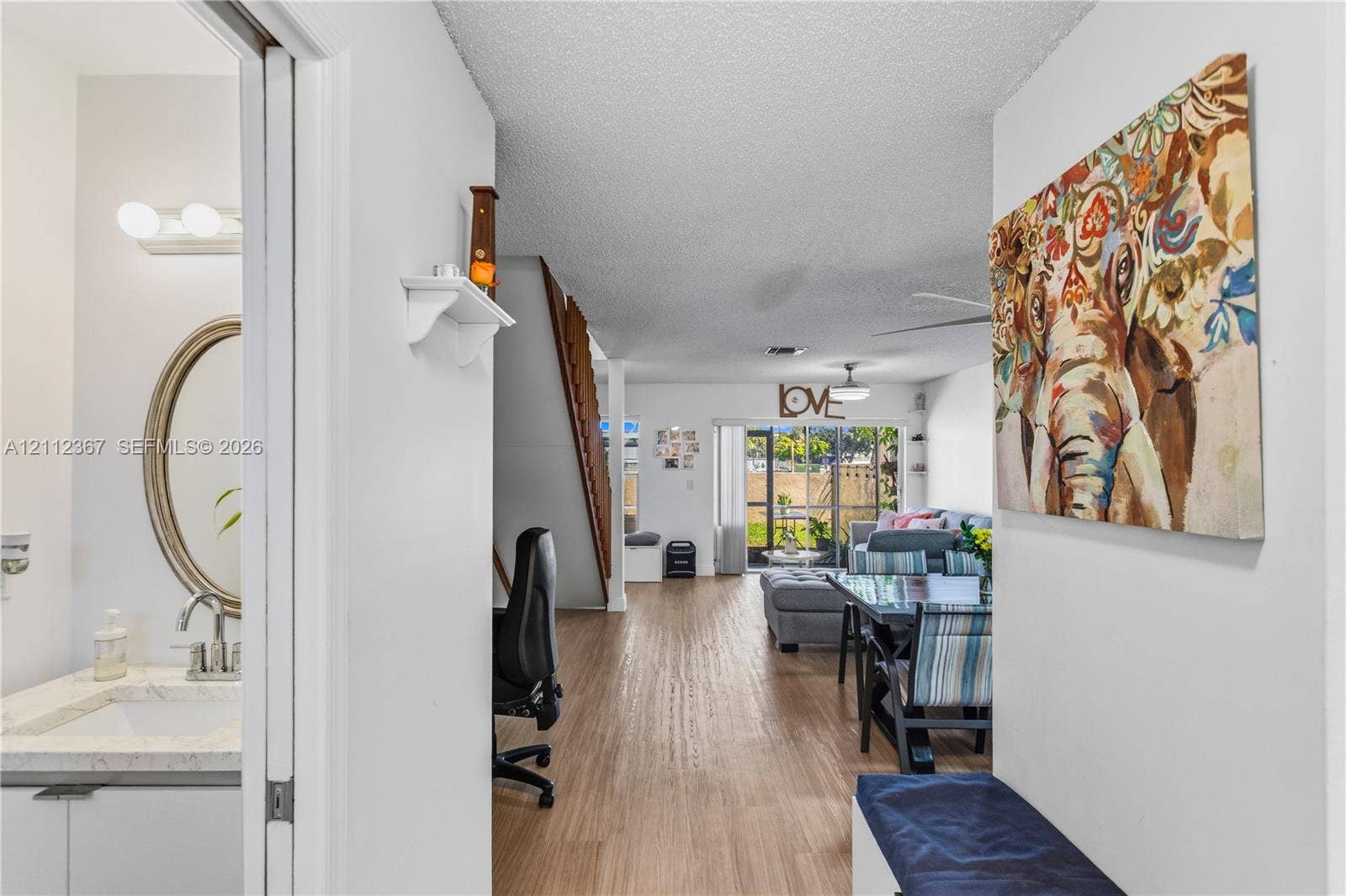 10803 Cypress Glen Drive, #10803, Coral Springs, FL 33071 Interior space featuring wood-finish flooring, a bathroom with an oval mirror and vanity, a staircase with wooden railings, and sliding glass doors