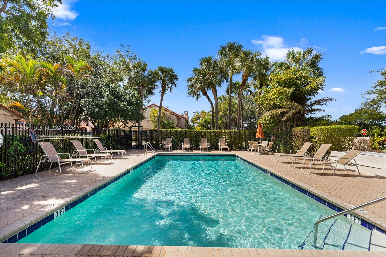 10803 Cypress Glen Drive, #10803, Coral Springs, FL 33071 Rectangular swimming pool featuring a brick paver deck, metal safety fencing, and stepped entry