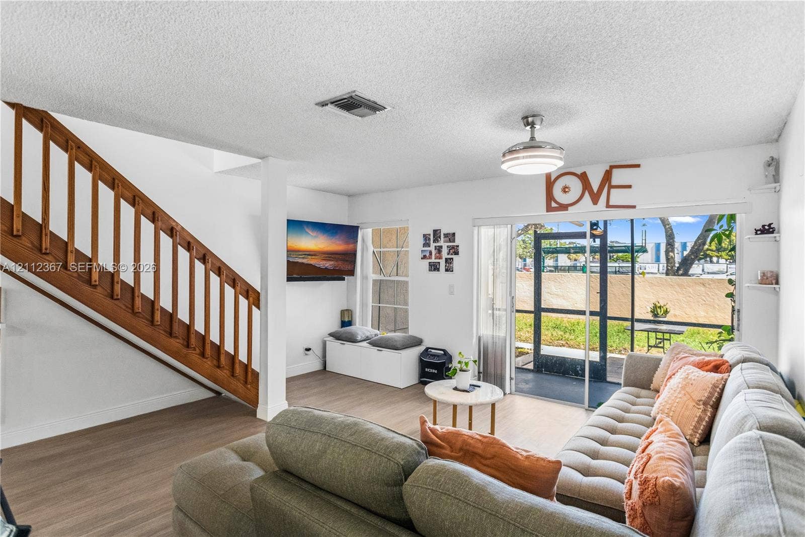 10803 Cypress Glen Drive, #10803, Coral Springs, FL 33071 Living area featuring wood-finish flooring, a wooden staircase with integrated railing, a ceiling-mounted light fixture with fan, and a sliding glass door providing external access