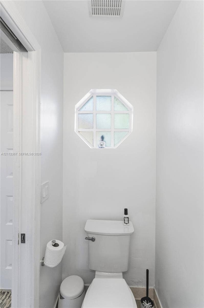 10803 Cypress Glen Drive, #10803, Coral Springs, FL 33071 Octagonal window with grid muntins, wall-mounted toilet paper dispenser, and high-profile white toilet