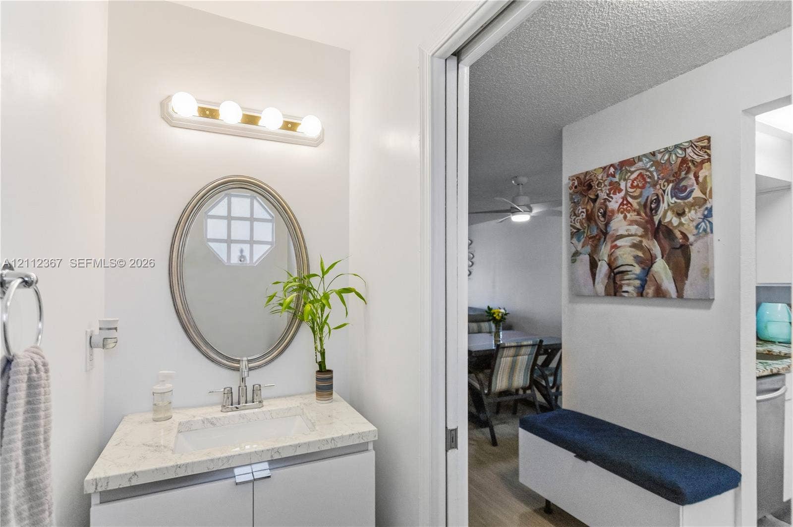 10803 Cypress Glen Drive, #10803, Coral Springs, FL 33071 Bathroom vanity featuring a stone-composite countertop, undermount sink, oval wall-mounted mirror, and a four-light fixture