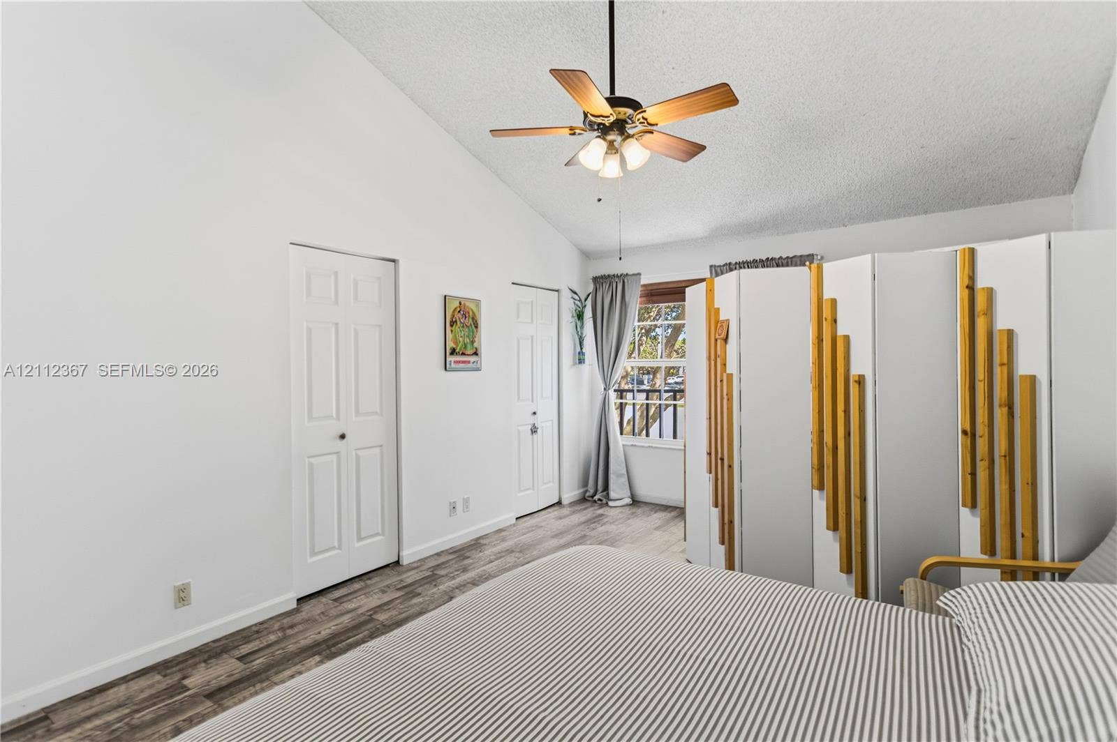 10803 Cypress Glen Drive, #10803, Coral Springs, FL 33071 Vaulted ceiling with a centrally mounted ceiling fan, wood-finish flooring, and two interior doors featuring white-finished panels