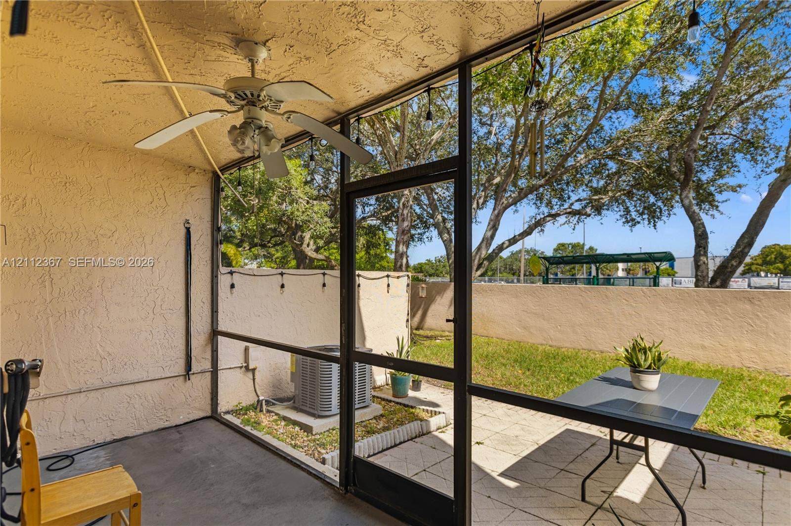 10803 Cypress Glen Drive, #10803, Coral Springs, FL 33071 Screened-in patio featuring a textured ceiling, ceiling fan with light fixture, concrete flooring, and a paved outdoor area