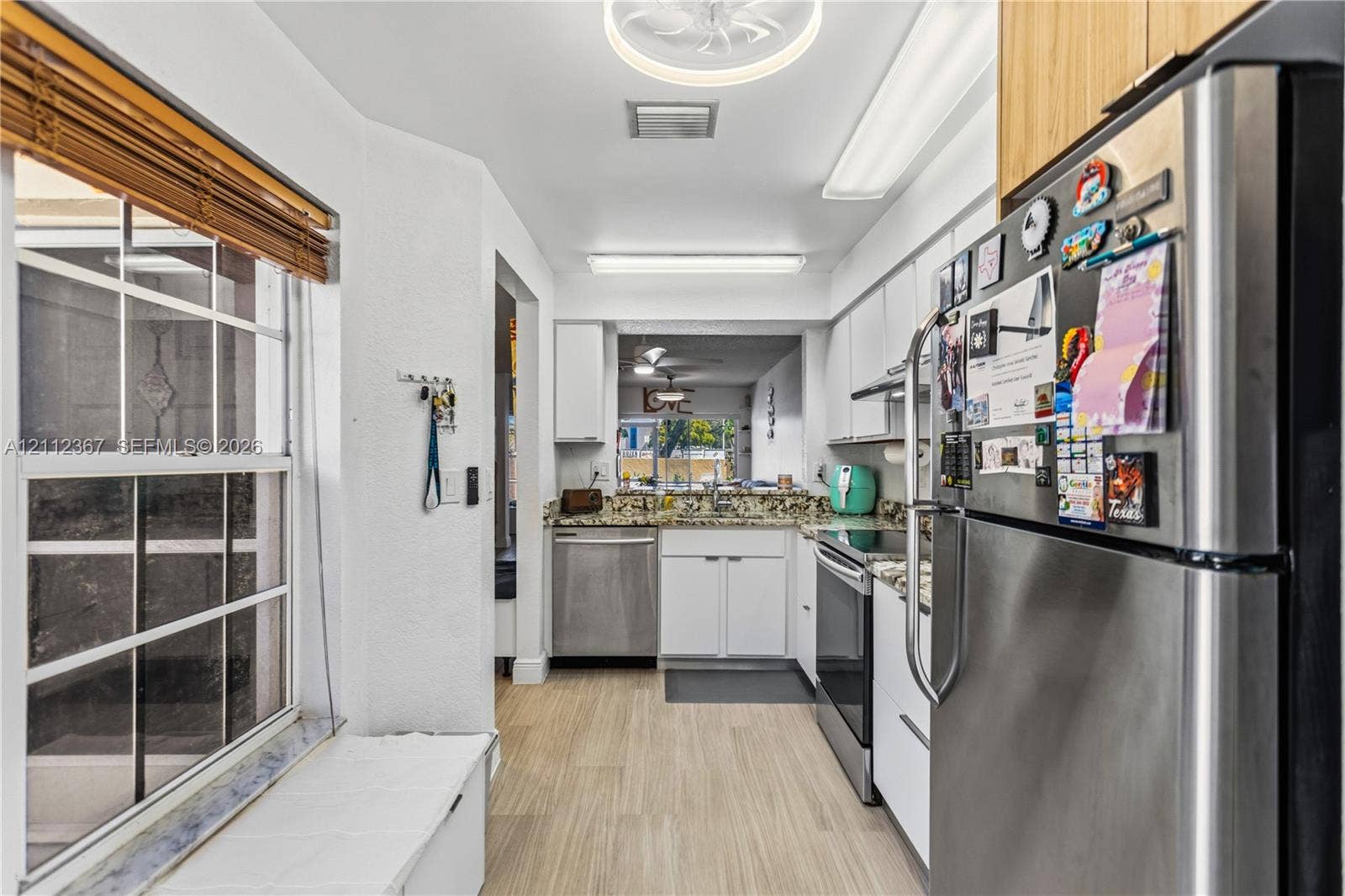 10803 Cypress Glen Drive, #10803, Coral Springs, FL 33071 Kitchen featuring stainless steel appliances, white cabinetry, stone-surface countertops, and wood-finish flooring