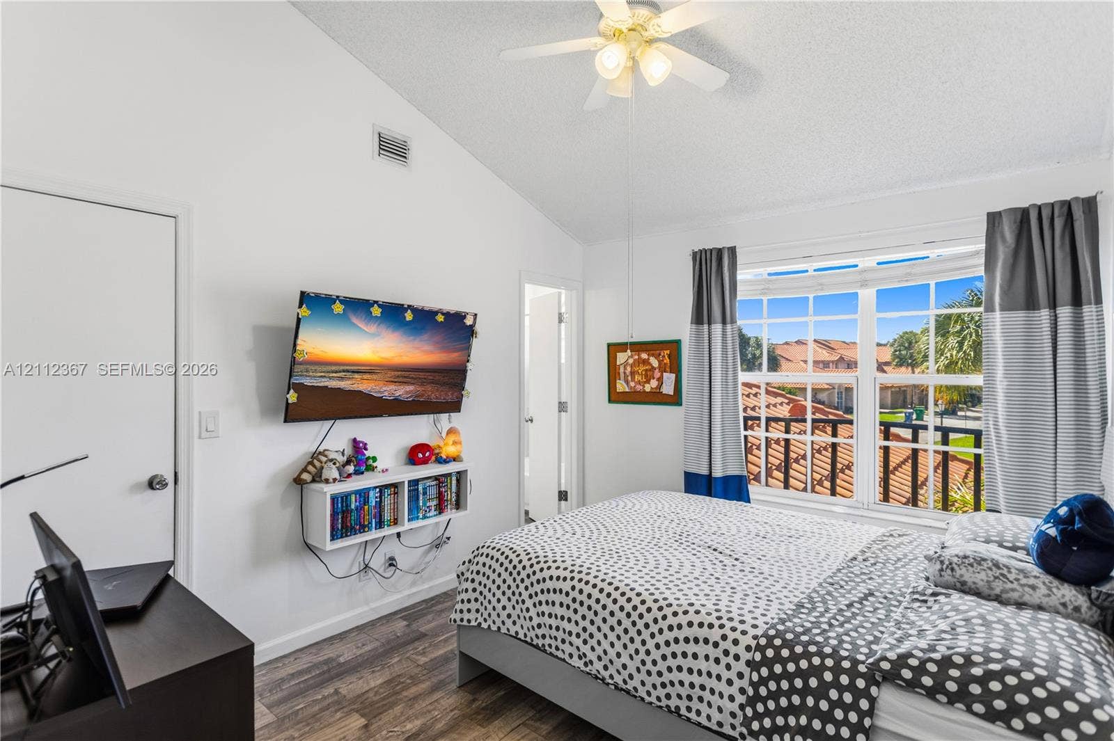 10803 Cypress Glen Drive, #10803, Coral Springs, FL 33071 Vaulted ceiling with integrated multi-blade ceiling fan and wood-finish flooring, complemented by a large multi-pane window with grid detailing