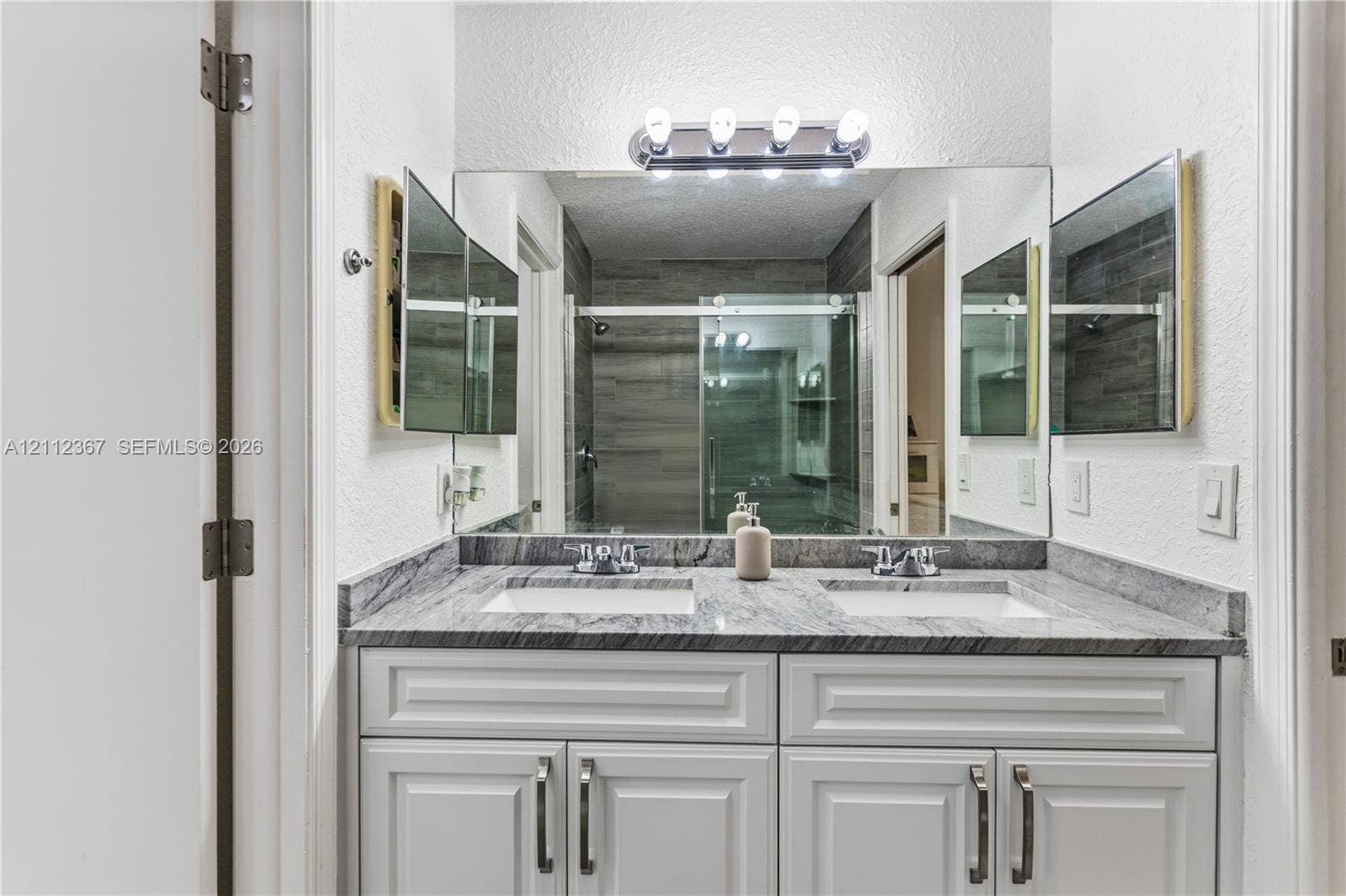 10803 Cypress Glen Drive, #10803, Coral Springs, FL 33071 Double vanity featuring a stone countertop, dual undermount sinks, white cabinetry with silver hardware, and a large wall-mounted mirror