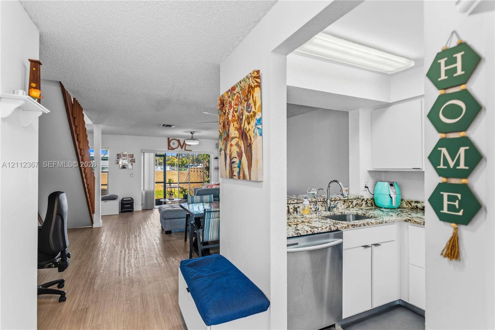 10803 Cypress Glen Drive, #10803, Coral Springs, FL 33071 Kitchen featuring stone-finish countertops, stainless steel dishwasher, and white cabinetry, paired with wood-finish flooring and a staircase with an open-riser design