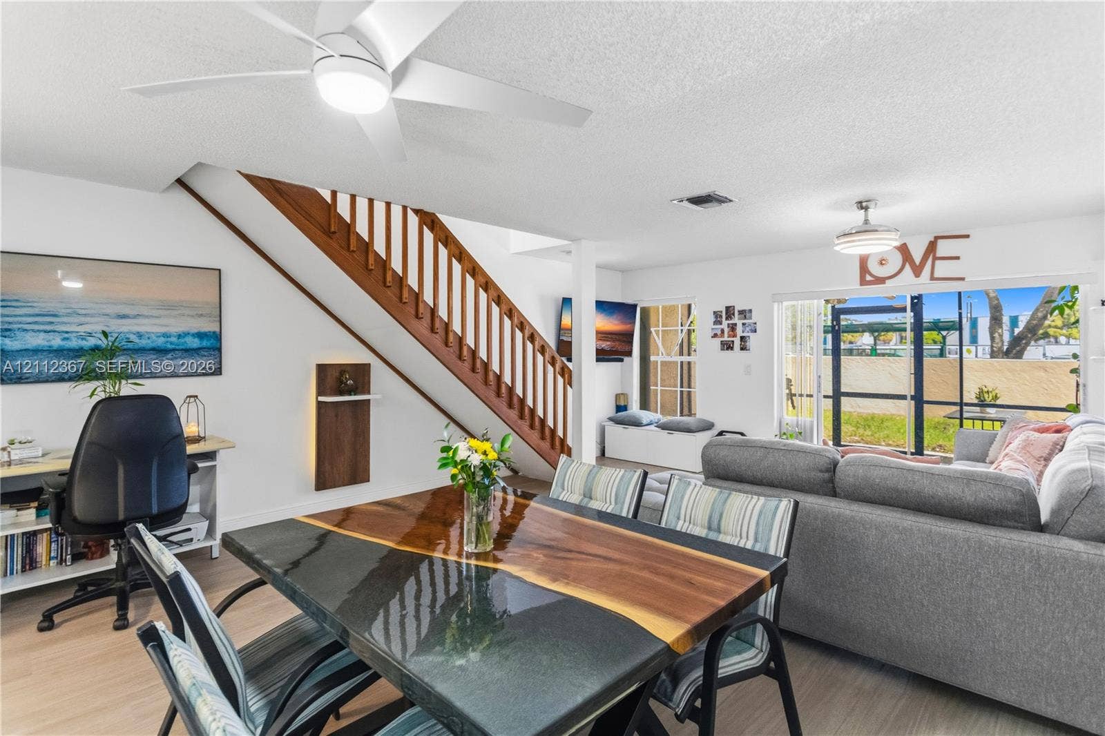 10803 Cypress Glen Drive, #10803, Coral Springs, FL 33071 Open living area featuring wood-finish flooring, a staircase with wooden balusters, dual ceiling fans with integrated lighting, and glass sliding doors