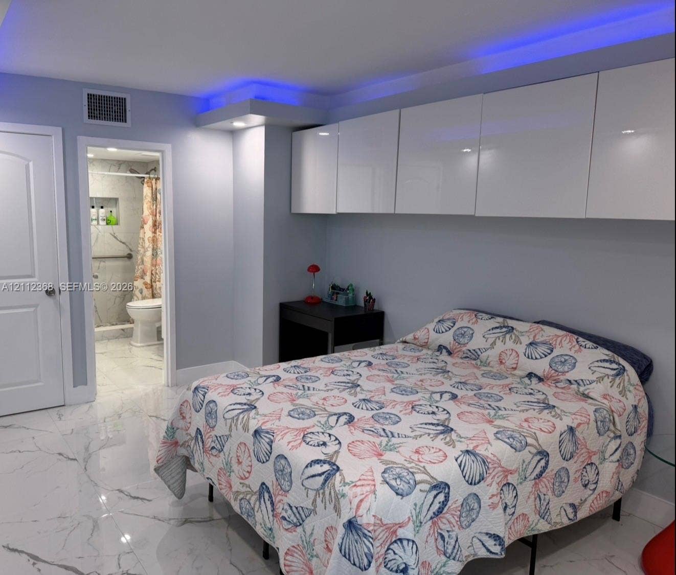 Large-format tile flooring with veining, white high-gloss wall-mounted cabinetry, recessed ceiling accent lighting, and a walk-in shower with tiled walls
