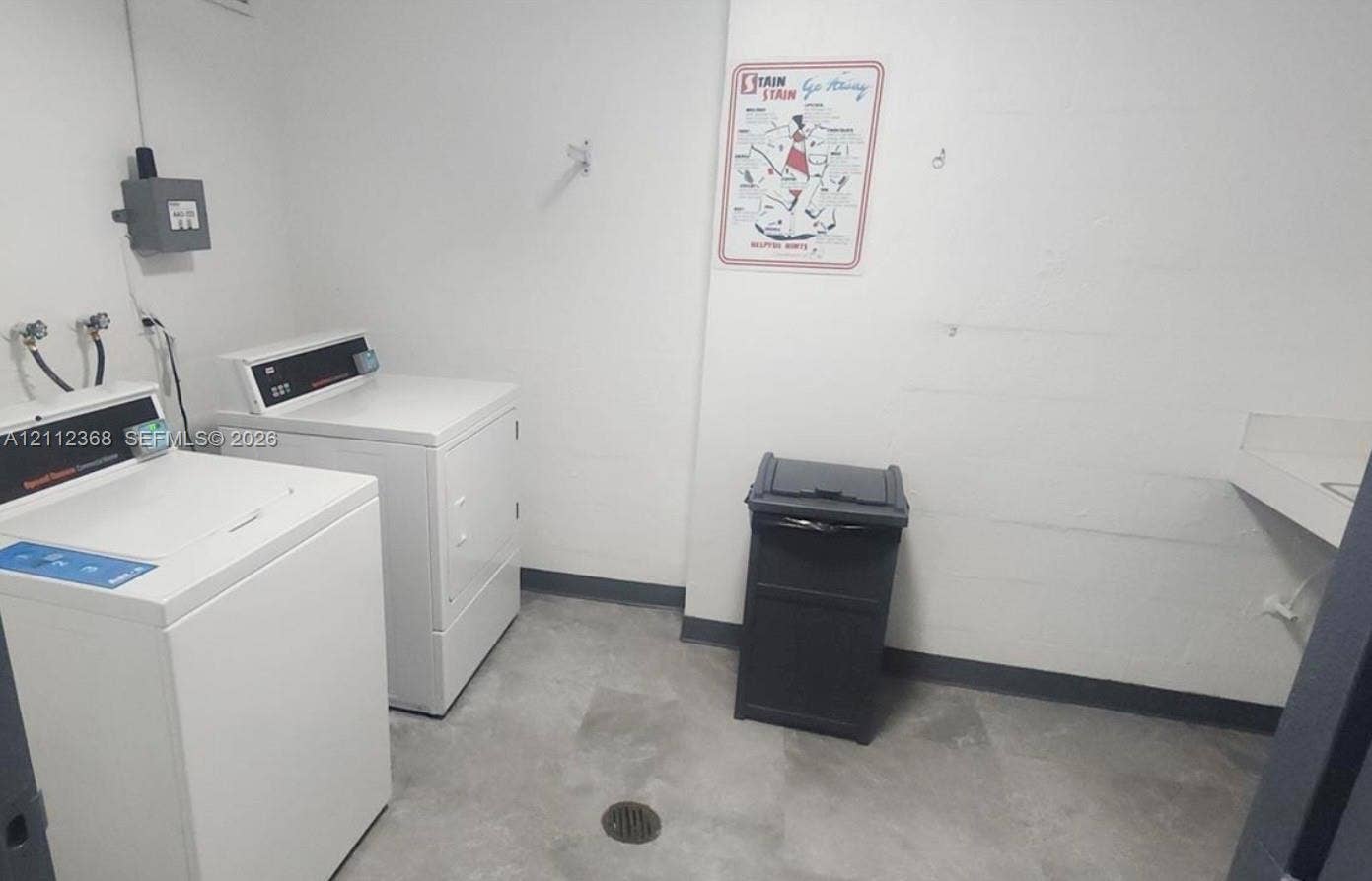 Utility room featuring large-format tile flooring, dedicated washer and dryer hookups, and a built-in wall-mounted sink basin