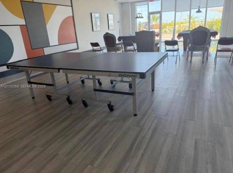 Spacious common area featuring wood-finish flooring, floor-to-ceiling windows, and recessed pendant lighting