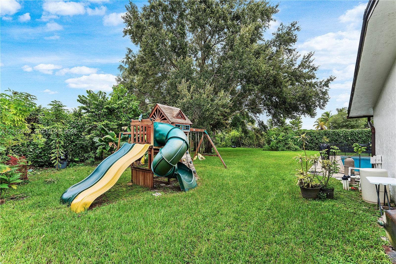10936 NW 41st Drive, Coral Springs, Coral Springs, FL 33065 Expansive rear yard featuring a manicured lawn, mature trees, and perimeter hedging
