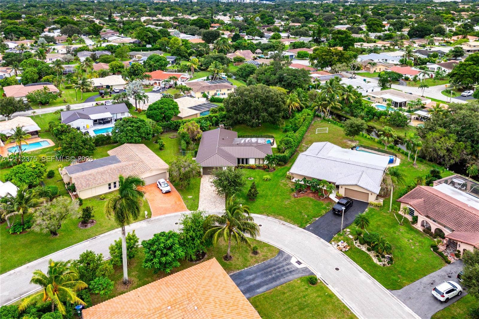 10936 NW 41st Drive, Coral Springs, Coral Springs, FL 33065 Aerial perspective of a suburban neighborhood featuring mature landscaping, winding roads, and expansive green spaces