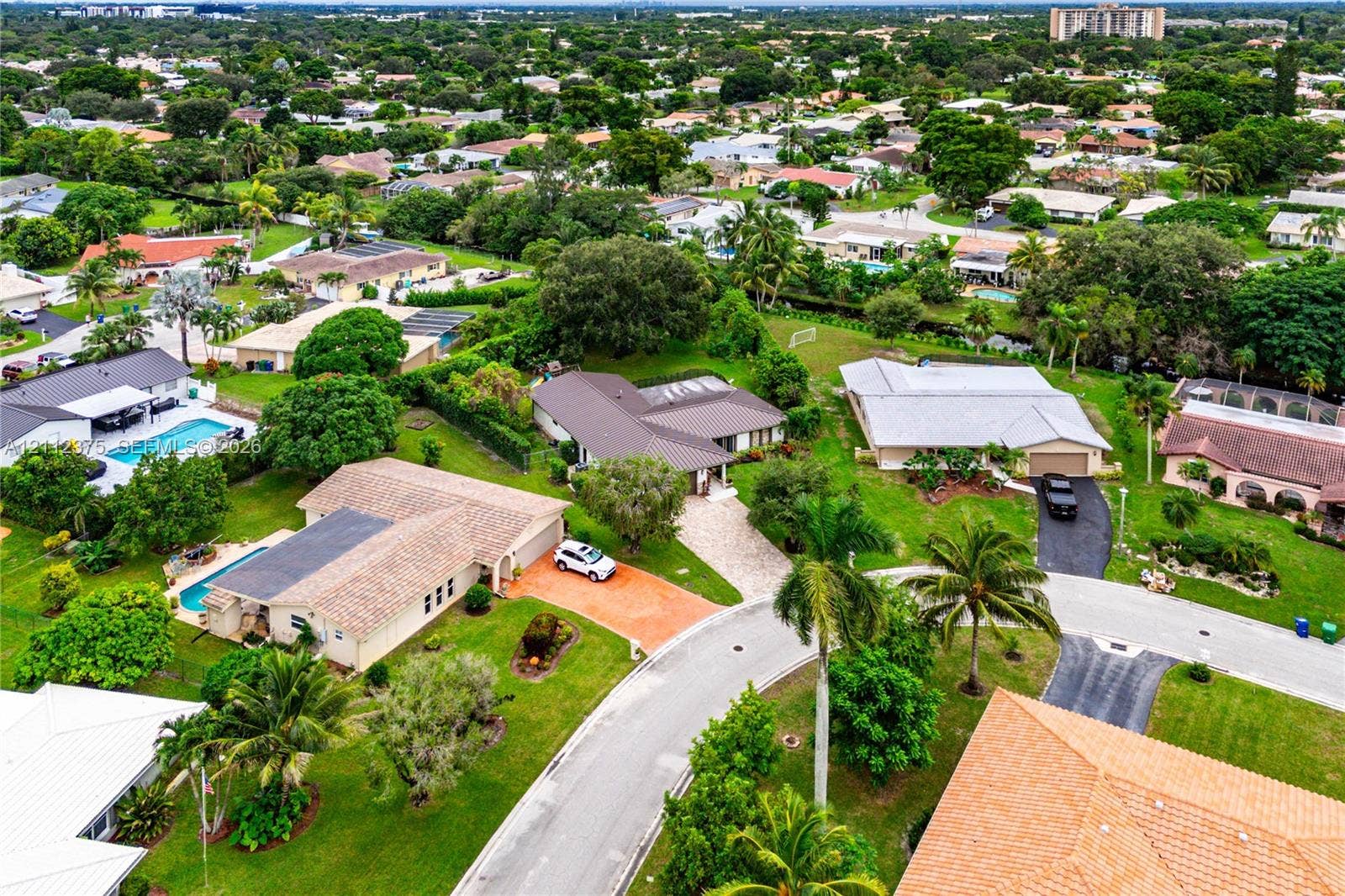 10936 NW 41st Drive, Coral Springs, Coral Springs, FL 33065 Aerial perspective of a suburban neighborhood featuring paved cul-de-sac streets, mature tropical landscaping, residential properties with shingled roofing, and private swimming pools