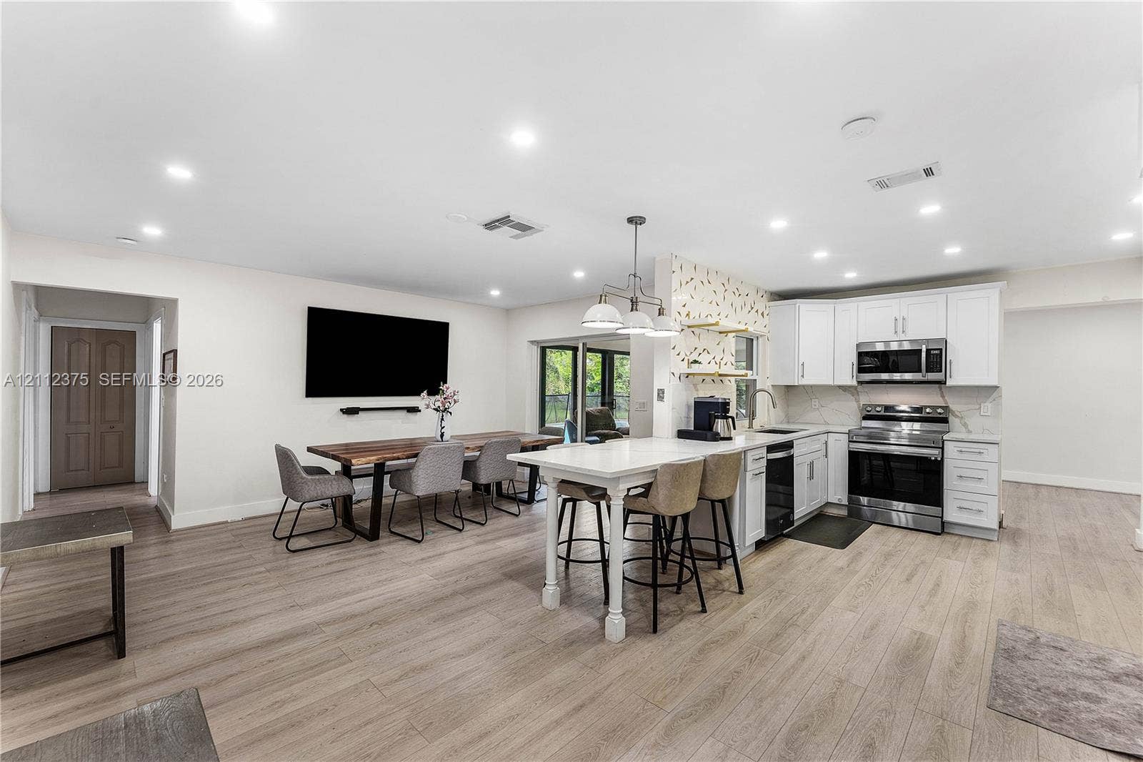 10936 NW 41st Drive, Coral Springs, Coral Springs, FL 33065 Kitchen featuring white cabinetry, stainless steel appliances, a central island with counter seating, recessed lighting, and wood-finish flooring
