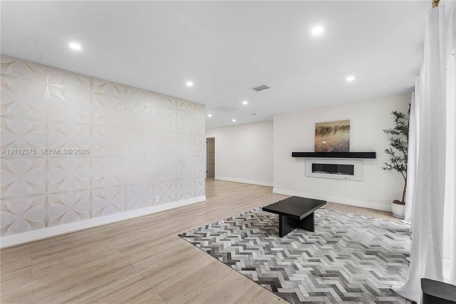 10936 NW 41st Drive, Coral Springs, Coral Springs, FL 33065 Living area featuring light-toned wood-finish flooring, recessed lighting, a patterned textured accent wall, and a linear wall-mounted electric fireplace with a floating mantel