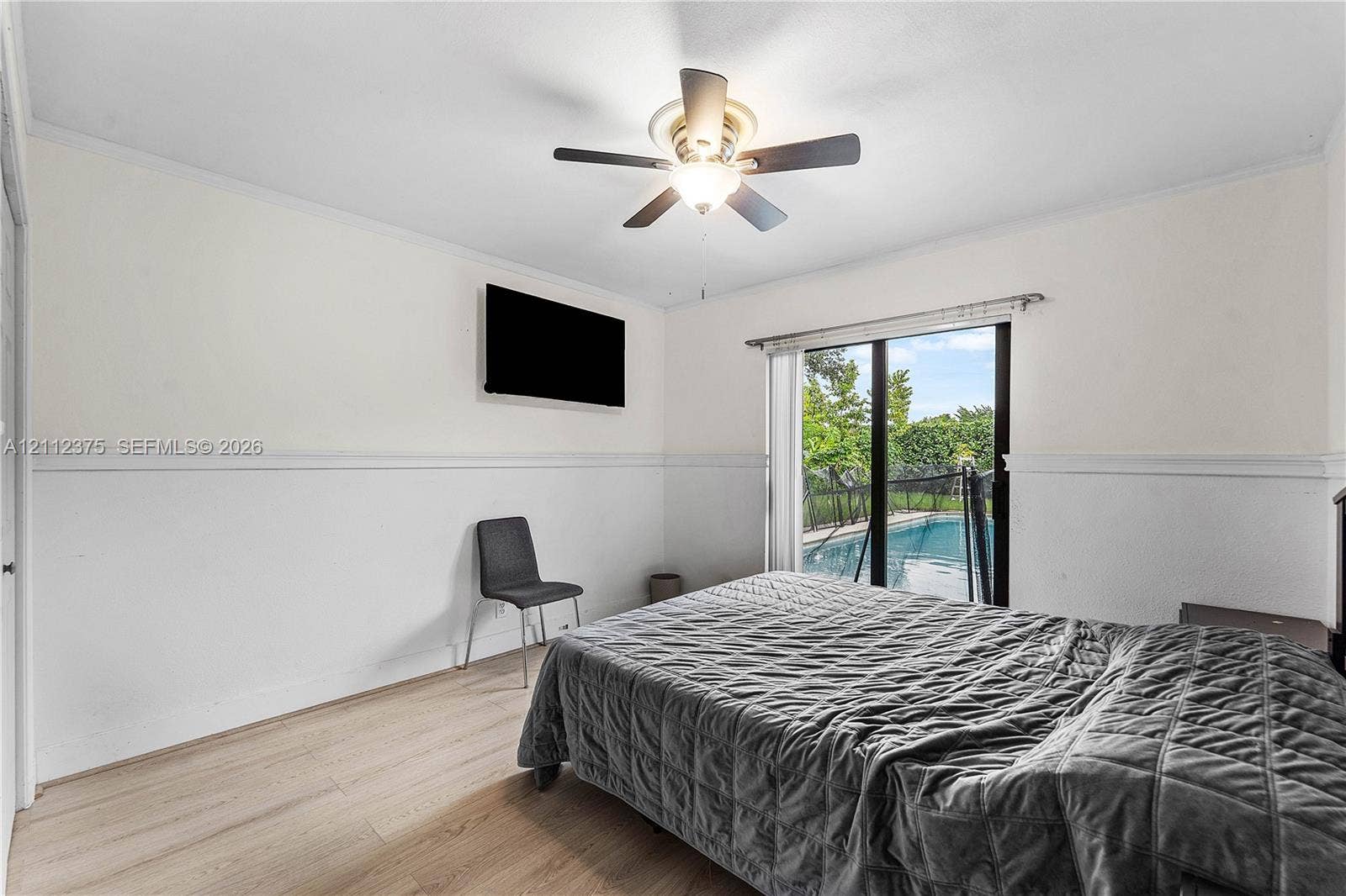 10936 NW 41st Drive, Coral Springs, Coral Springs, FL 33065 Neutral-toned interior featuring wood-finish flooring, chair rail molding, ceiling fan with integrated lighting, and glass sliding doors