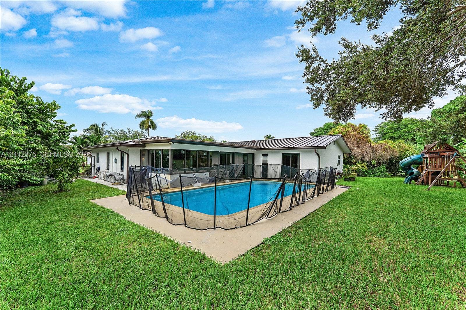 10936 NW 41st Drive, Coral Springs, Coral Springs, FL 33065 Private backyard featuring an in-ground swimming pool, concrete pool deck, and expansive lawn area