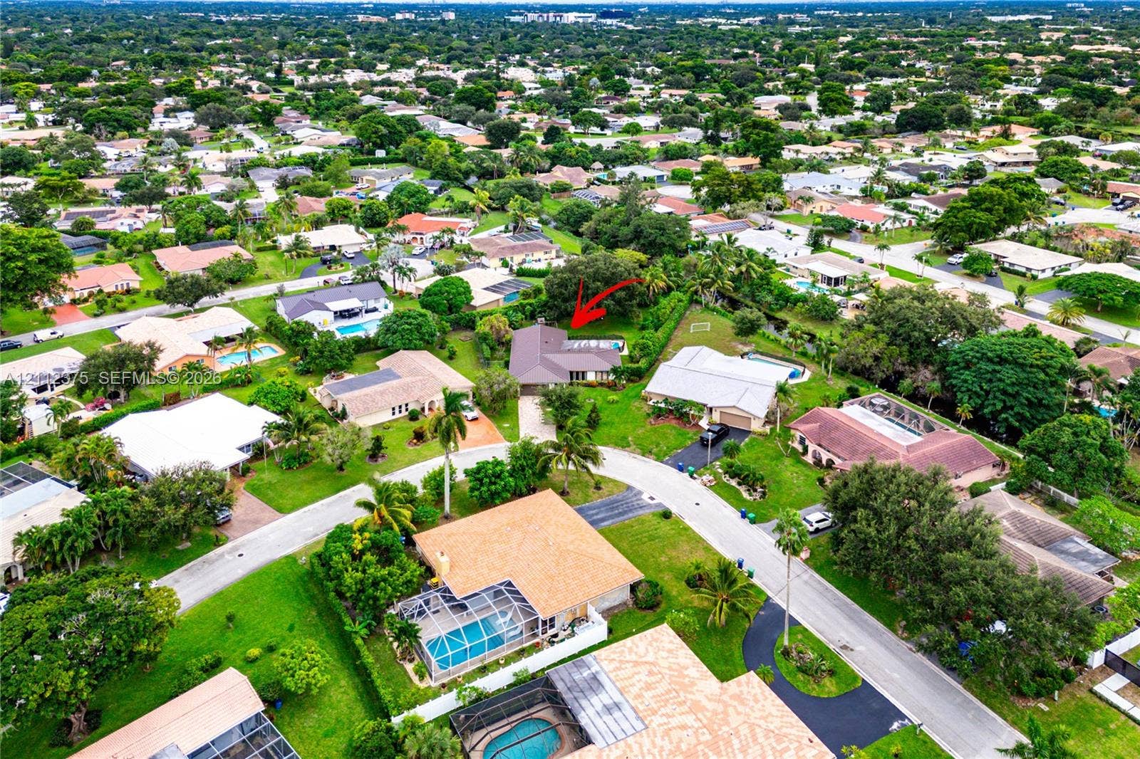 10936 NW 41st Drive, Coral Springs, Coral Springs, FL 33065 Aerial perspective of a single-story residence featuring a shingled roof, a paved driveway, and a rear swimming pool
