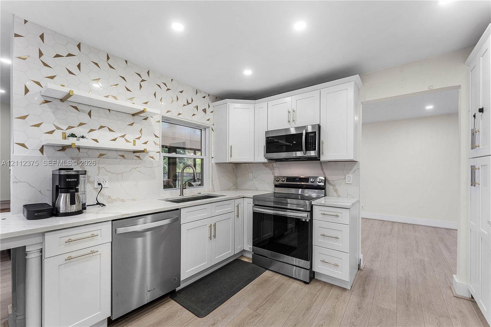10936 NW 41st Drive, Coral Springs, Coral Springs, FL 33065 Kitchen featuring white shaker-style cabinetry, quartz countertops, geometric pattern backsplash, wood-finish flooring, and stainless steel appliances