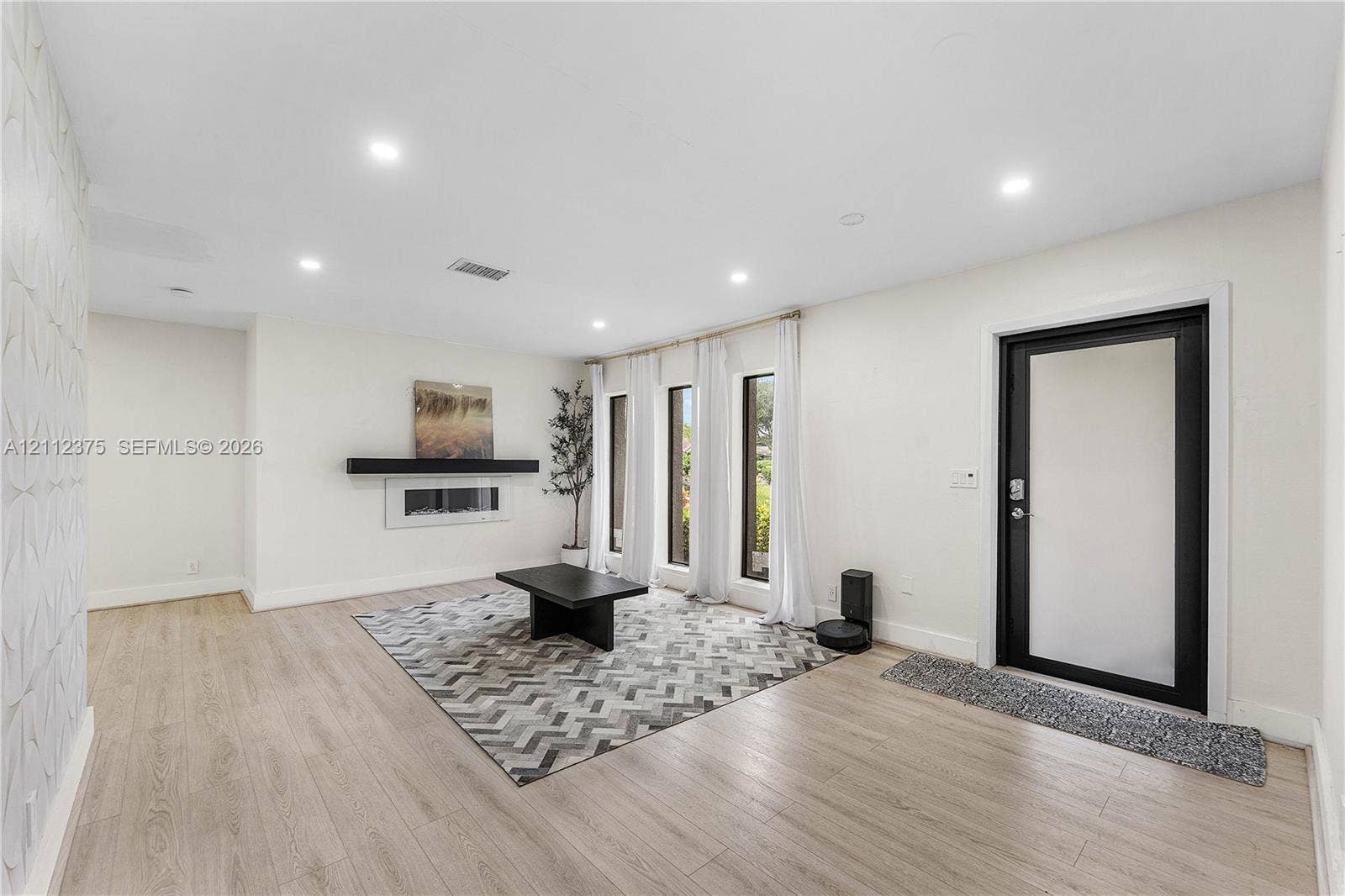 10936 NW 41st Drive, Coral Springs, Coral Springs, FL 33065 Open-concept room featuring wood-finish flooring, recessed lighting, a textured accent wall, and a linear wall-mounted fireplace with a mantel