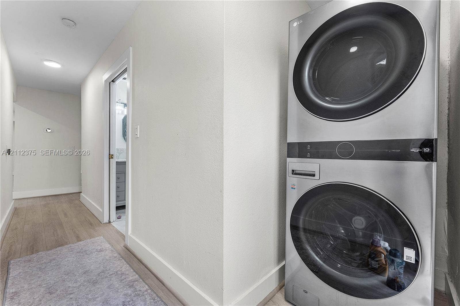 10936 NW 41st Drive, Coral Springs, Coral Springs, FL 33065 Laundry closet featuring a stackable stainless-steel washer and dryer unit with wood-finish flooring