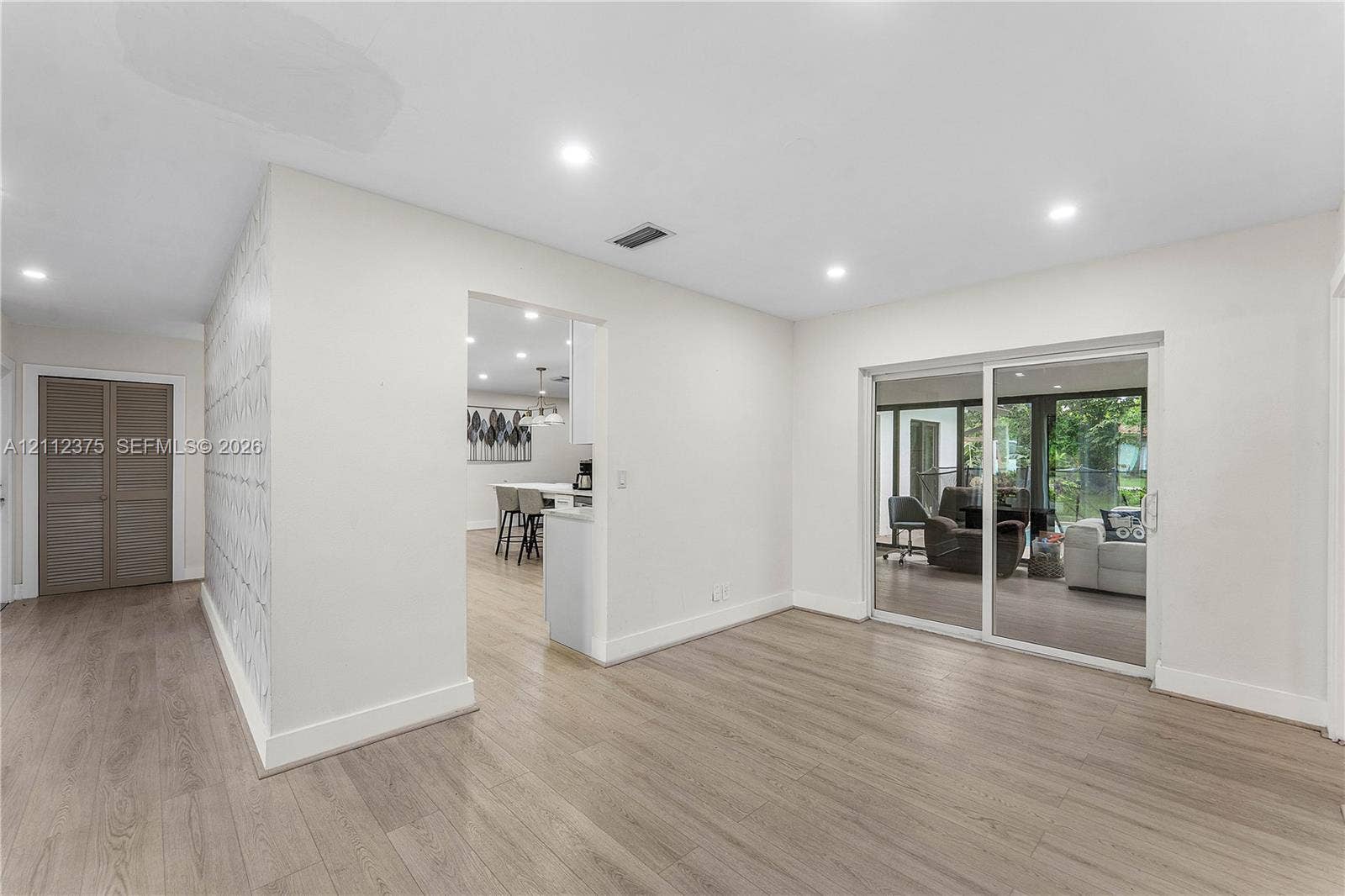 10936 NW 41st Drive, Coral Springs, Coral Springs, FL 33065 Interior featuring wood-finish flooring, recessed lighting, sliding glass doors, and patterned accent wall