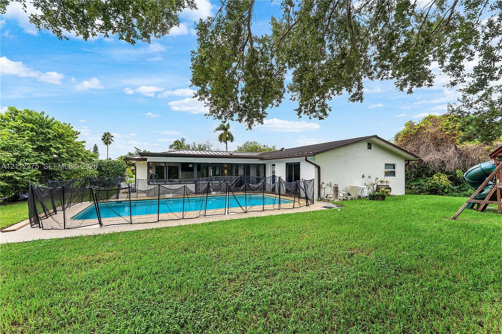 10936 NW 41st Drive, Coral Springs, Coral Springs, FL 33065 Exterior featuring a swimming pool with a surrounding concrete deck and mature shade trees