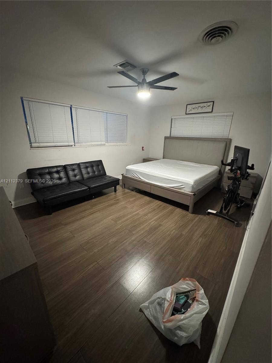19600 NE 18th Place, Miami, FL 33179 Room featuring wood-finish flooring, a multi-blade ceiling fan with integrated lighting, and horizontal slatted window blinds