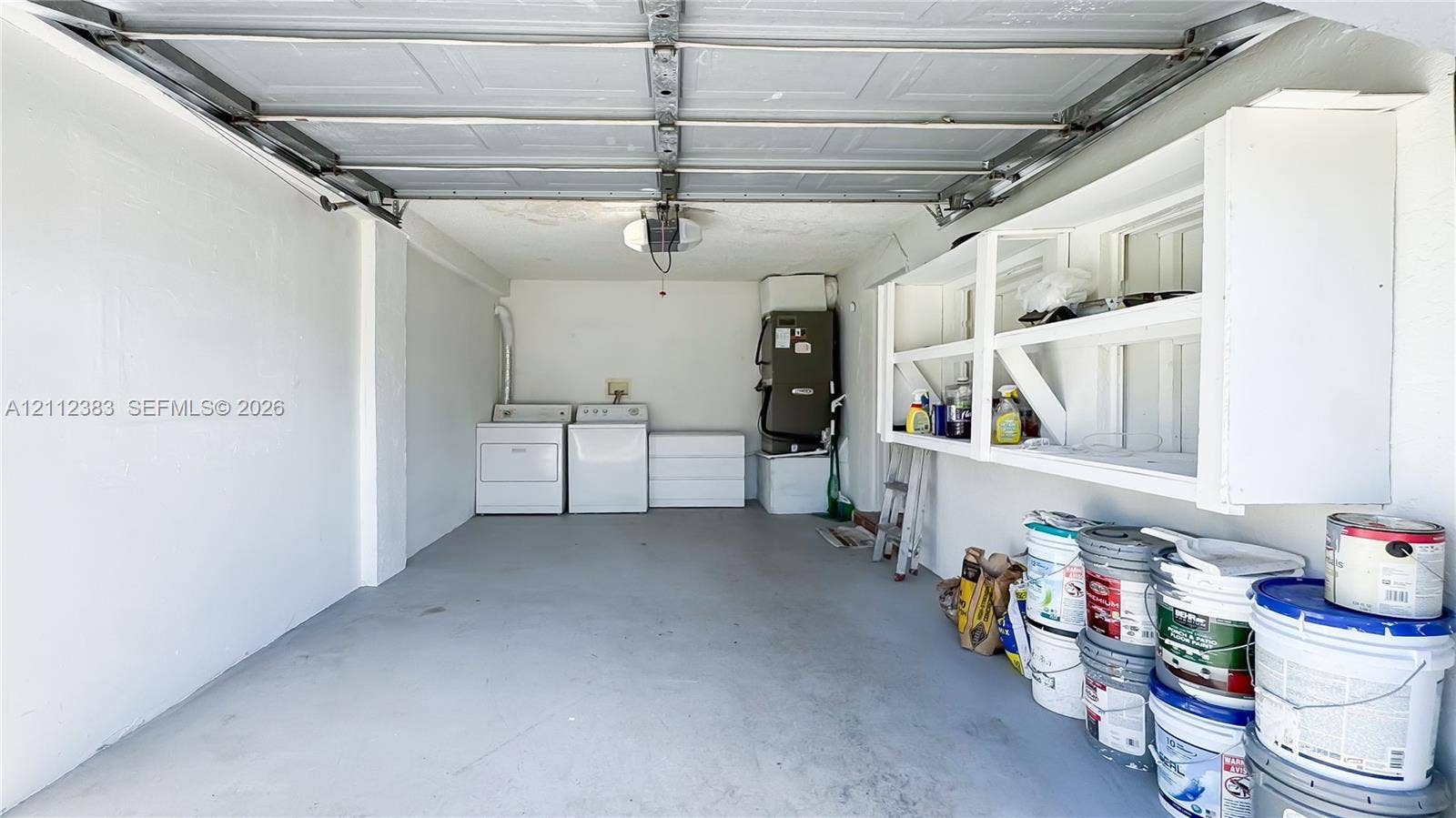5319 Lake Boulevard, Delray Beach, Delray Beach, FL 33484 Enclosed garage space featuring overhead sectional door, dedicated laundry area with side-by-side connections, and built-in wall-mounted shelving units