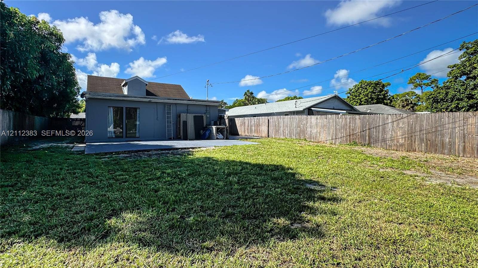 5319 Lake Boulevard, Delray Beach, Delray Beach, FL 33484 Expansive backyard featuring a grass lawn, privacy fencing, and a concrete patio