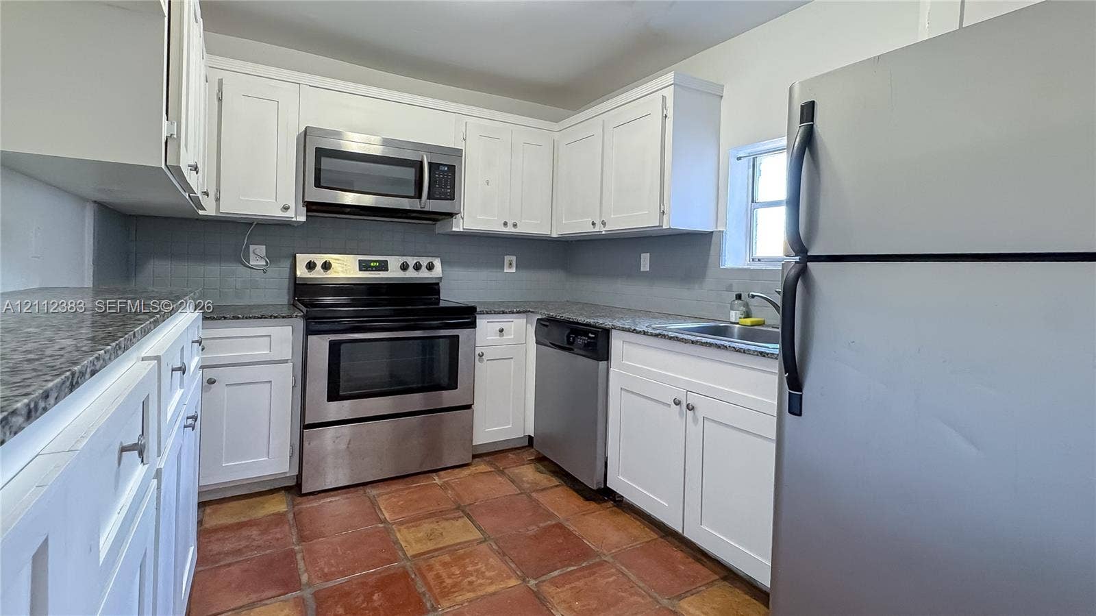 5319 Lake Boulevard, Delray Beach, Delray Beach, FL 33484 Kitchen featuring white shaker-style cabinetry, speckled stone-finish countertops, stainless steel appliances, and terracotta-style tile flooring