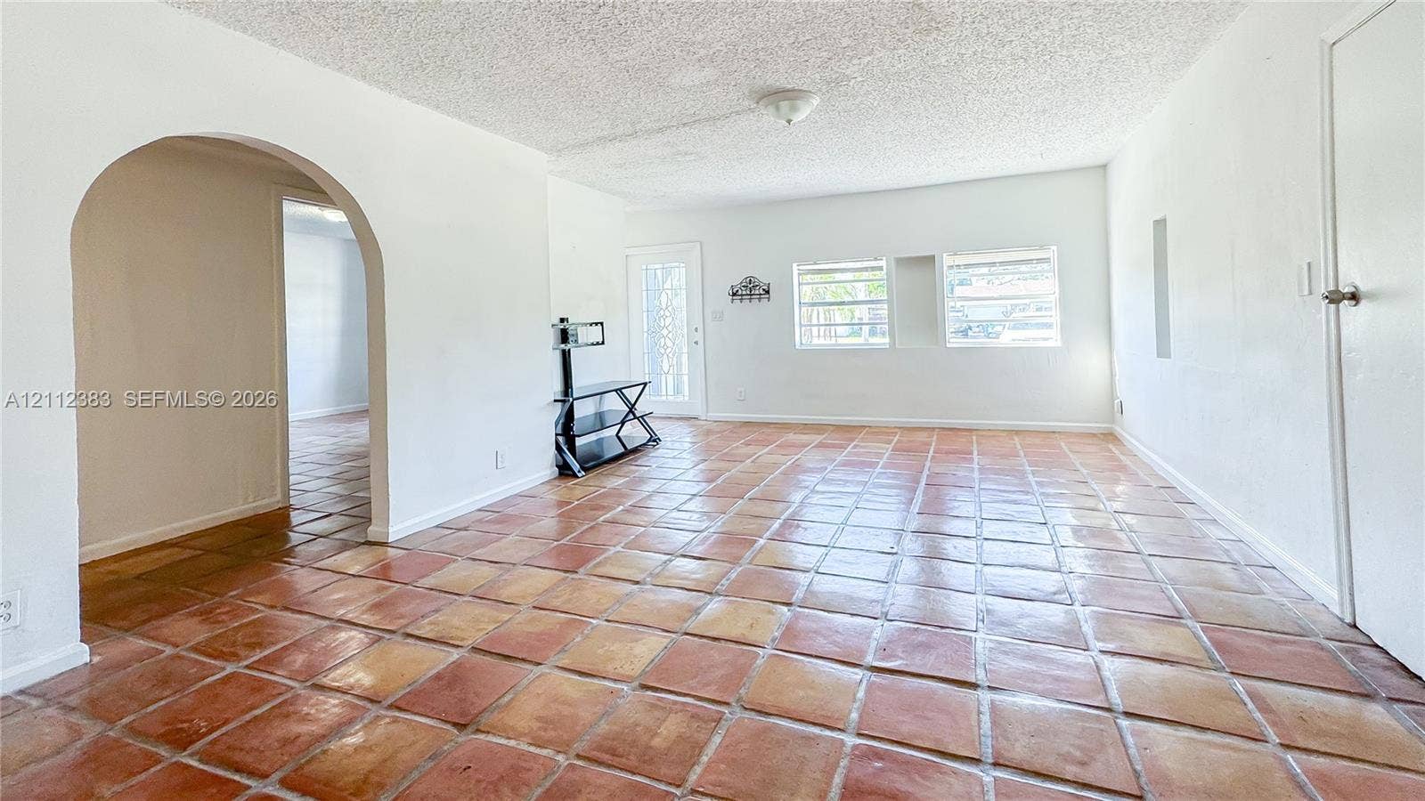 5319 Lake Boulevard, Delray Beach, Delray Beach, FL 33484 Interior space featuring natural stone-finish tile flooring, an arched entryway, and a full-light glass panel exterior door