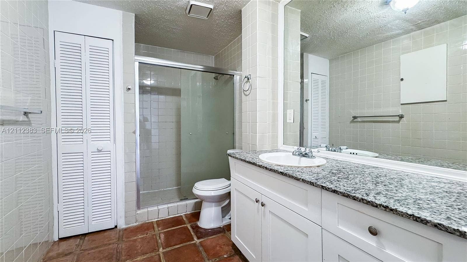 5319 Lake Boulevard, Delray Beach, Delray Beach, FL 33484 Bathroom featuring a vanity with a stone countertop, an integrated sink, a large wall-mounted mirror, a glass-enclosed shower, and tile flooring