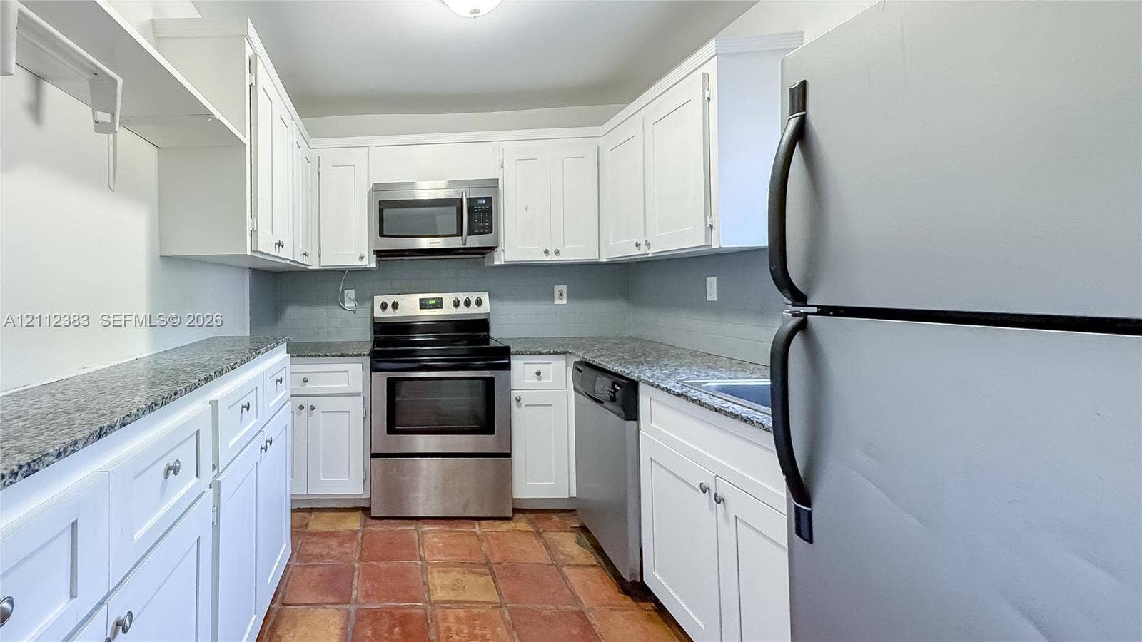 5319 Lake Boulevard, Delray Beach, Delray Beach, FL 33484 Kitchen featuring white cabinetry, stone-finish countertops, stainless steel appliances, and terra-cotta tile flooring