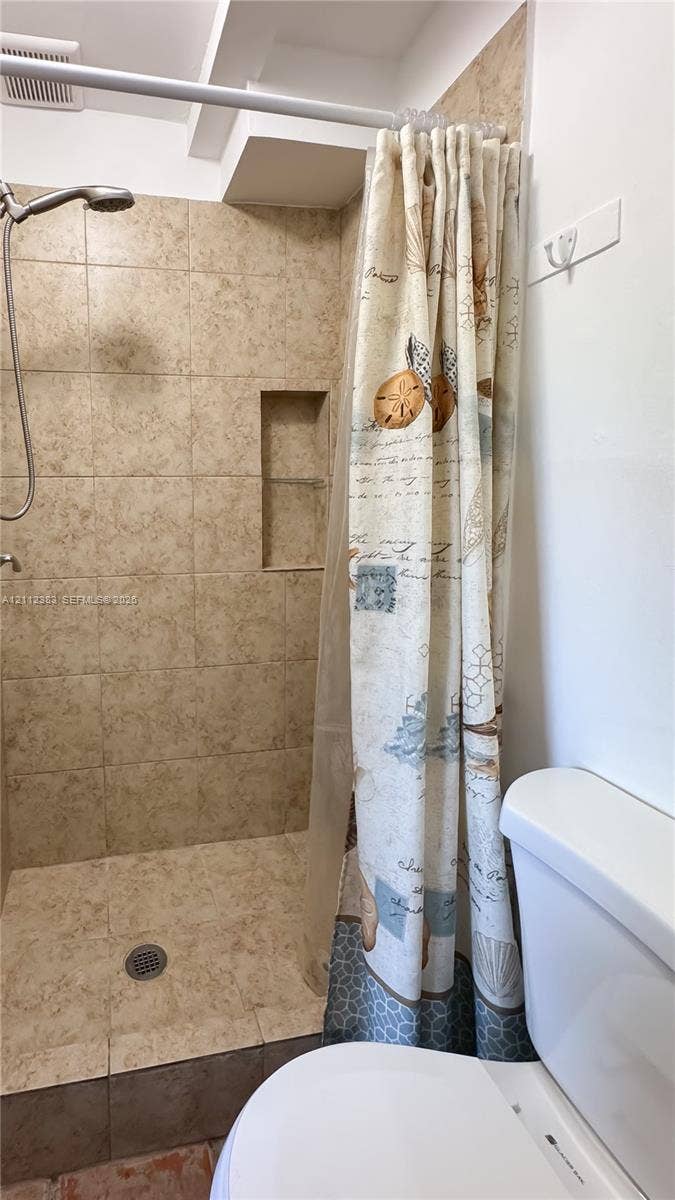 5319 Lake Boulevard, Delray Beach, Delray Beach, FL 33484 Walk-in shower featuring floor-to-ceiling tile, a built-in recessed storage niche, and a wall-mounted shower head