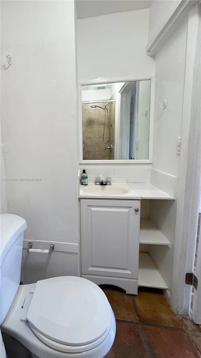 5319 Lake Boulevard, Delray Beach, Delray Beach, FL 33484 Bathroom featuring a vanity with integrated shelving, inset sink, framed wall mirror, and terra-cotta tile flooring