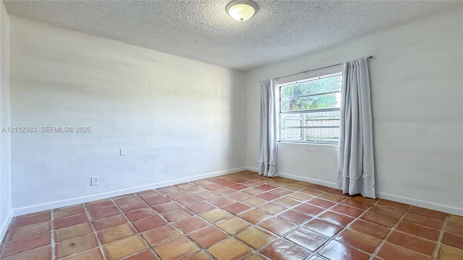 5319 Lake Boulevard, Delray Beach, Delray Beach, FL 33484 Interior space featuring terracotta-style tile flooring, textured ceiling, central flush-mount lighting, and a single-hung window